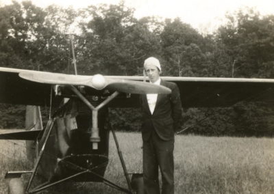 Black and white photo of young man in front of plane. Early 1900s